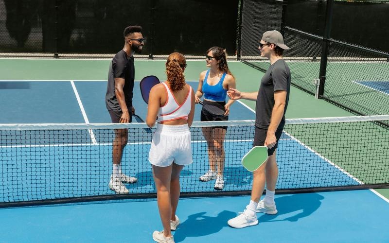 A group of people standing on a pickleball court.