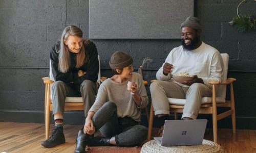friends sit together around an open laptop