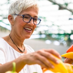 a woman smiling and holding a bunch of vegetables