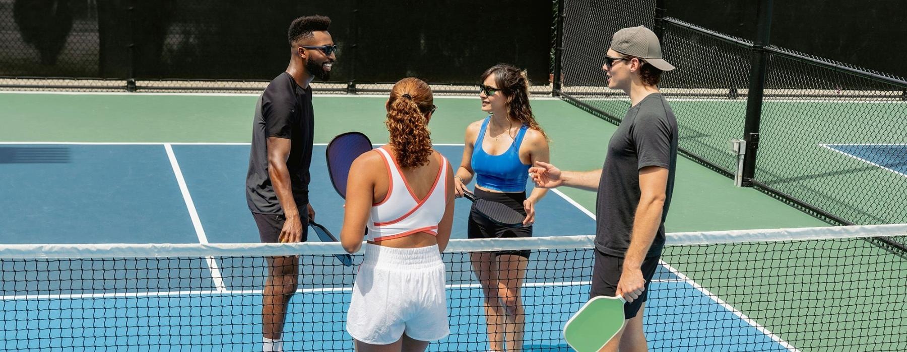 A group of people standing on a pickleball court.